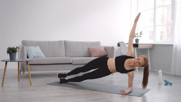 Exercice féminin de planche de coude latéral avec le bras levé à l'intérieur — Video