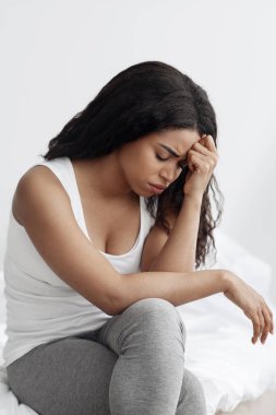 Duyarsızlık konsepti. Üzgün Afrikalı Amerikalı kadın erkek arkadaşıyla tartıştıktan sonra üzgün hissediyor, yatakta oturuyor.