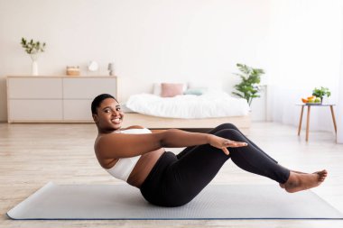 Kilolu siyahi kadın karın egzersizi yapıyor, vücut kaslarını evde çalıştırıyor, uzayı kopyalıyor.