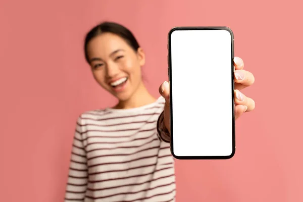 Great App. Веселая азиатка демонстрирует смартфон с чистым белым экраном — стоковое фото