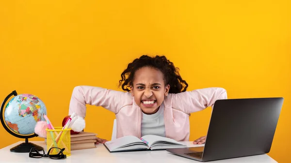 Furiosa menina da escola africana olhando para a câmera usando laptop — Fotografia de Stock