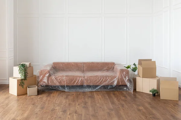 Empty living room with couch, stacks of boxes during relocation — Stock Photo, Image