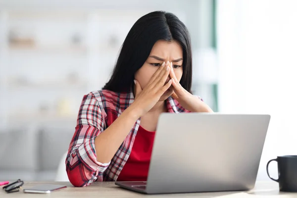 Stresowana azjatycka freelancer kobieta patrząc na ekranie laptopa z niepokojem — Zdjęcie stockowe