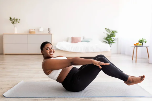 Sobrepeso milenaria dama negra haciendo ejercicios abdominales, los músculos del núcleo de entrenamiento en casa, espacio de copia — Foto de Stock