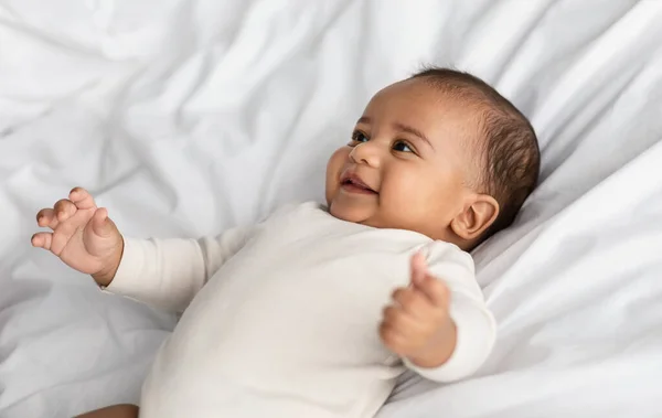 Bebê afro-americano bonito deitado na cama e rindo — Fotografia de Stock