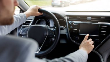 Yeni araba kullanan adam koltukta oturur, direksiyonu modern otomatikte tutar.