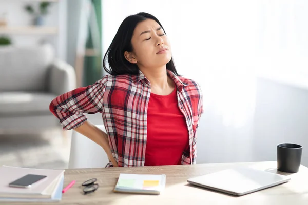 Bella giovane donna asiatica che soffre di mal di schiena mentre lavora in Home Office — Foto Stock