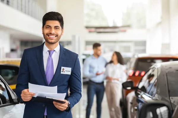 Charismatic árabe vendedor assistente posando sobre auto showroom — Fotografia de Stock