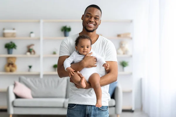 Concepto de paternidad. feliz joven negro hombre celebración lindo recién nacido bebé en manos — Foto de Stock