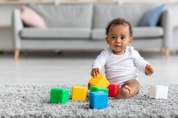 Adorable bebé bebé negro jugando con apilar bloques de construcción en casa —  Fotos de Stock