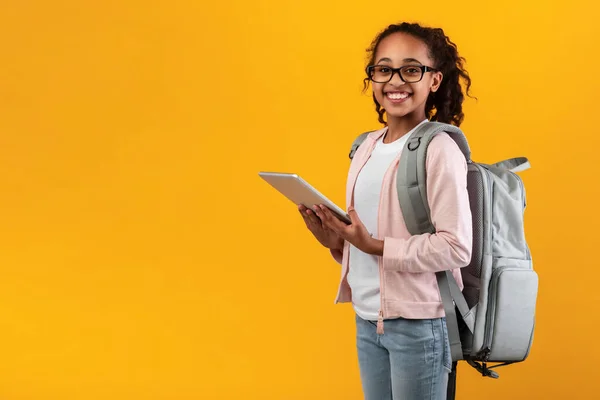 Zwart meisje met tablet in de gele studiowand — Stockfoto