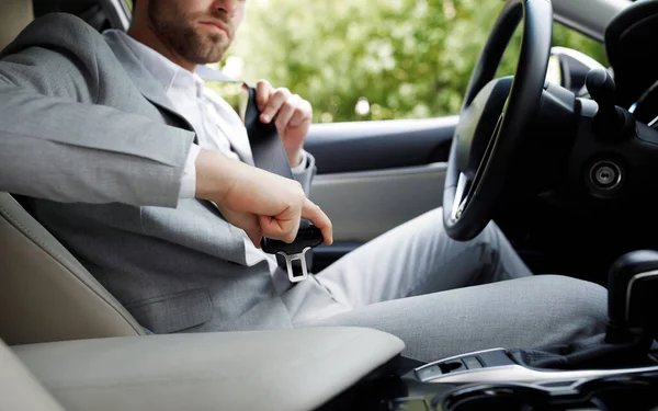 Esteja seguro cara jovem sentado no assento de condução do carro, apertando cinto de segurança e pronto para ir — Fotografia de Stock