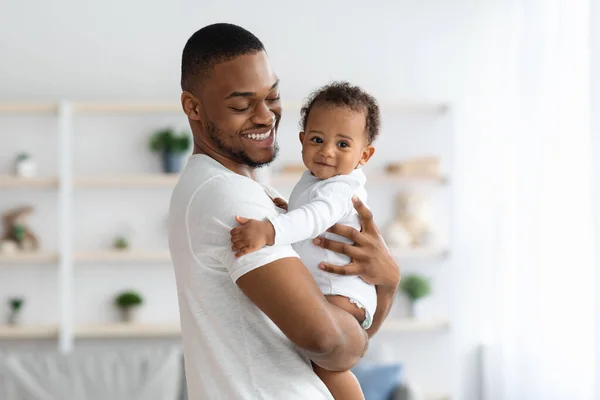 Feliz padre afroamericano acurrucando a su adorable hijo recién nacido en casa —  Fotos de Stock