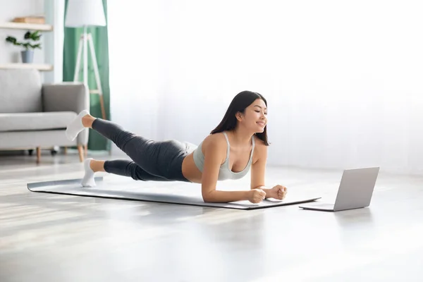 Sportlich asiatisch weiblich training im vorderseite von laptop bei zuhause — Stockfoto