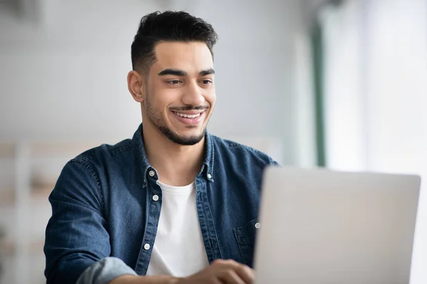 Närbild av glad arabiska killen som arbetar med bärbar dator på kontoret — Stockfoto