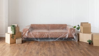 Oturma odasında örtülü kanepe, taşınma sırasında yığınla kutu.