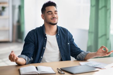 Genç Arap çalışanı stresli bir iş gününden sonra sakinleşiyor.