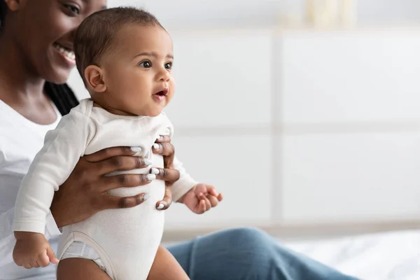 Svart mamma sitter på sängen med sin söta lilla bebis — Stockfoto