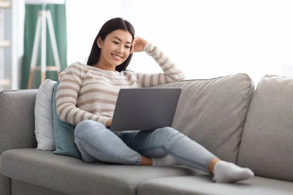 Felice giovane donna asiatica guardando film online sul computer portatile a casa — Foto Stock