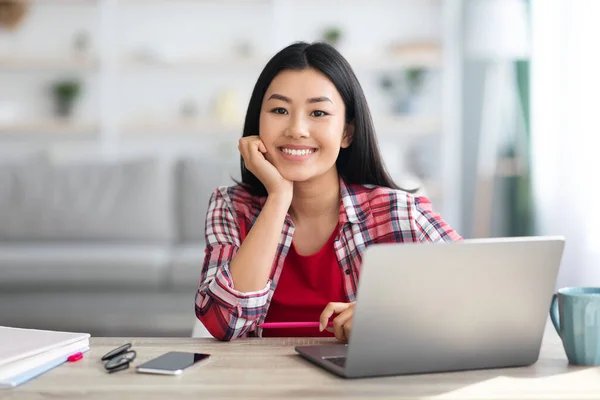 Porträt der schönen jungen asiatischen Freelancerin, die mit Laptop am Schreibtisch sitzt — Stockfoto
