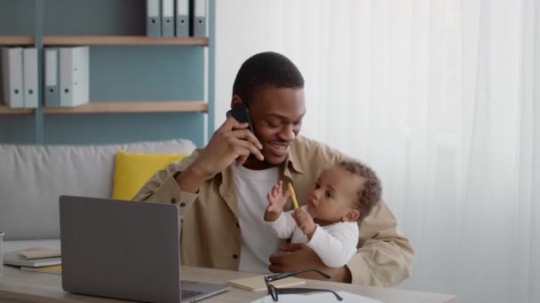 Amare il papà afroamericano che tiene il bambino per mano e lo bacia, discutendo di affari con i partner tramite cellulare — Video Stock