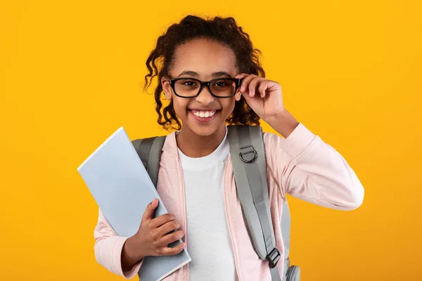 Уверенная в себе молодая черная девушка с учебниками, смотрящая в камеру — стоковое фото