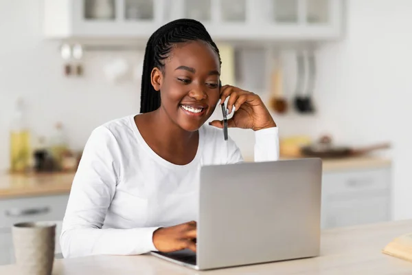 Sorridente donna nera che lavora su pc parlando al telefono — Foto Stock