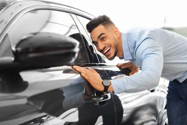 Bonito árabe homem comprar carro novo, verificando a superfície — Fotografia de Stock