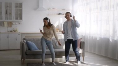 Genç Asyalı çift evde eğlenirken kulaklık takıyor.