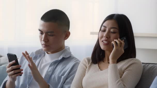 Azjatycka para korzystająca ze smartfonów i rozmawiająca przez telefon w domu — Wideo stockowe