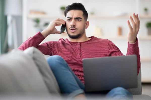 Wütender Mann mit Notizbuch auf dem Schoß telefoniert — Stockfoto