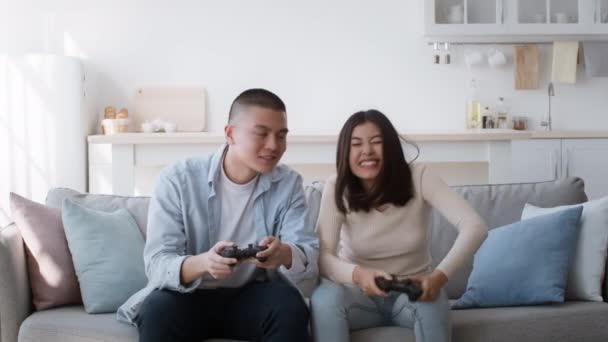 Koreańska para gra wideo siedzi na kanapie w domu — Wideo stockowe
