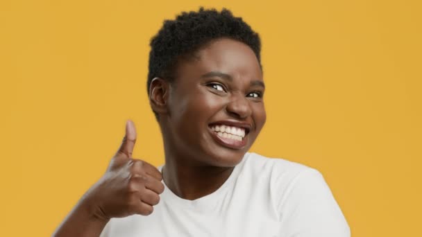 Vrolijke Afro-Amerikaanse vrouw met overgewicht die duimen opzuigt over gele achtergrond — Stockvideo