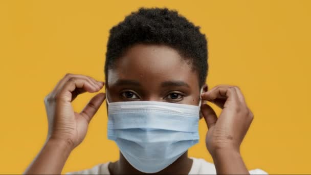 Black Woman Taking Off Face Mask Posing On Yellow Background — Stock Video