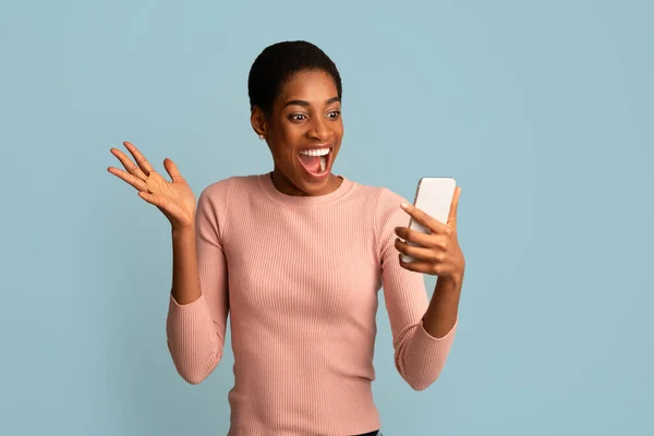 Mobilní nabídka. Nadšený africký americký dáma při pohledu na Smartphone obrazovky v ruce — Stock fotografie