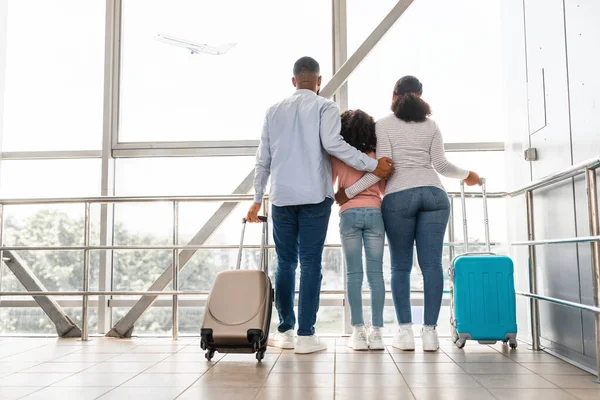 Czarna rodzina podróżuje, czeka na przylot samolotu — Zdjęcie stockowe