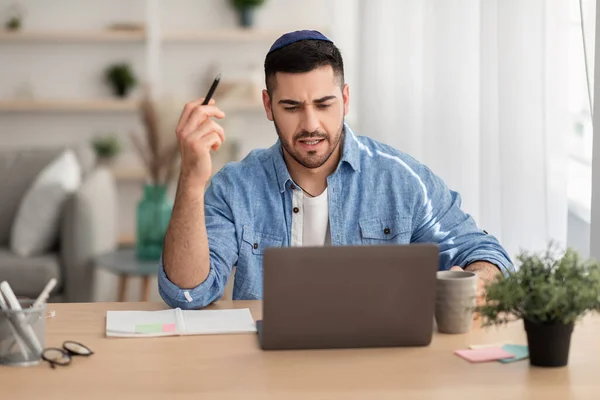 Hombre israelí enfocado trabajando en el ordenador portátil y escribiendo en casa — Foto de Stock