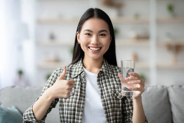 Mosolygó ázsiai hölgy bemutató üveg édesvízzel — Stock Fotó