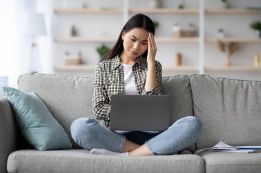 Şaşırmış Koreli serbest yazar dizüstü bilgisayar ekranına bakıyor.