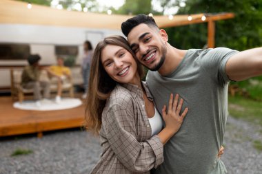 Sevecen, çok ırklı bir çift karavanın yanında selfie çekiyor arkadaşlarıyla dışarıda dinleniyor, mekanı kopyalıyor.
