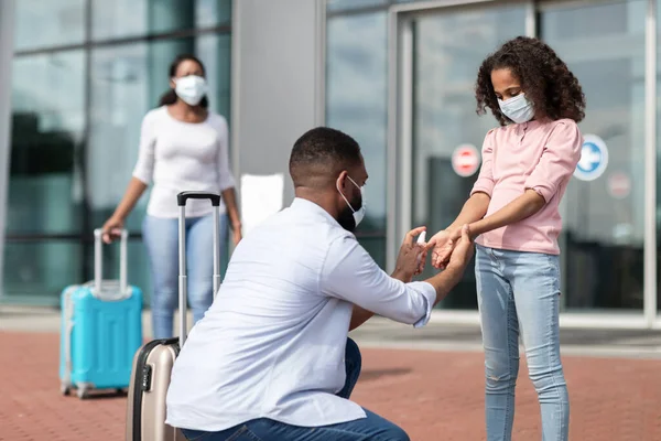 Negro familia viajando, hombre usando desinfectante en niñas manos —  Fotos de Stock