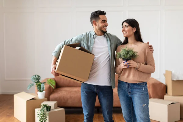 Feliz hombre y mujer sosteniendo caja de cartón y planta —  Fotos de Stock