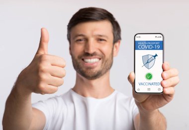 Mutlu adam covid-19 için immün dijital pasaportlu akıllı telefon gösteriyor.