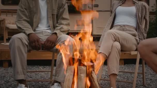 Nahaufnahme des brennenden Lagerfeuers beim Zelten, Gruppe diverser Freunde, die herumsitzen — Stockvideo