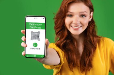 Genç kadın dijital sağlık pasaportlu akıllı telefon gösteriyor.