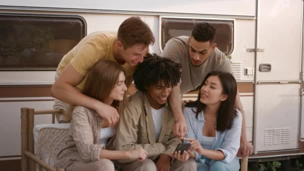 Grupo de jóvenes amigos multirraciales que usan teléfonos inteligentes juntos mientras se relajan en el camping — Vídeos de Stock
