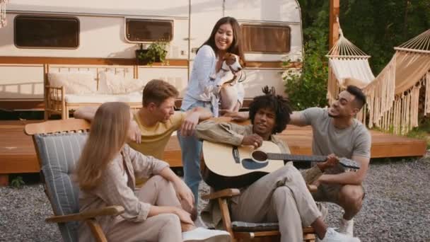 Wesoły wielorasowych znajomych bawiących się na kempingu, gra na gitarze i śpiewa razem — Wideo stockowe
