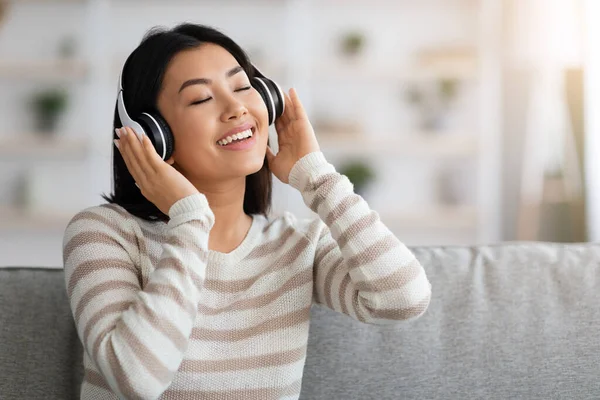 Porträt einer entspannten Asiatin mit Kopfhörern, die mit geschlossenen Augen Musik hört — Stockfoto