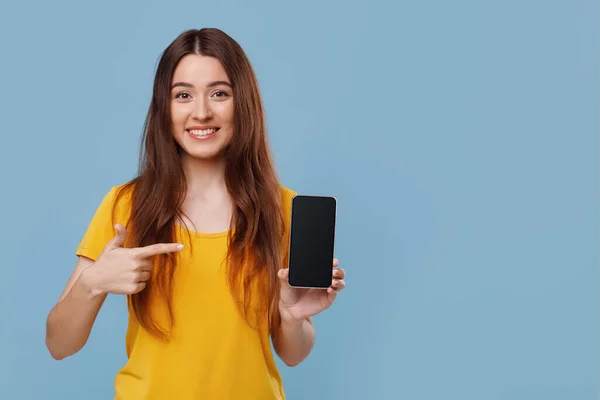 Vrolijke mooie dame wijzend naar smartphone met leeg scherm — Stockfoto