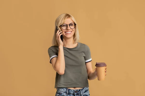 Vacker ung dam dricka hämtmat kaffe och prata på mobiltelefon över färgglada studio bakgrund — Stockfoto